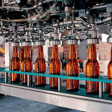Glasflasker bevæger sig gennem et produktionsanlæg til fremstilling af drikkevarer. Overvågning af opløst ilt er vigtig for at kunne styre produktkvaliteten.