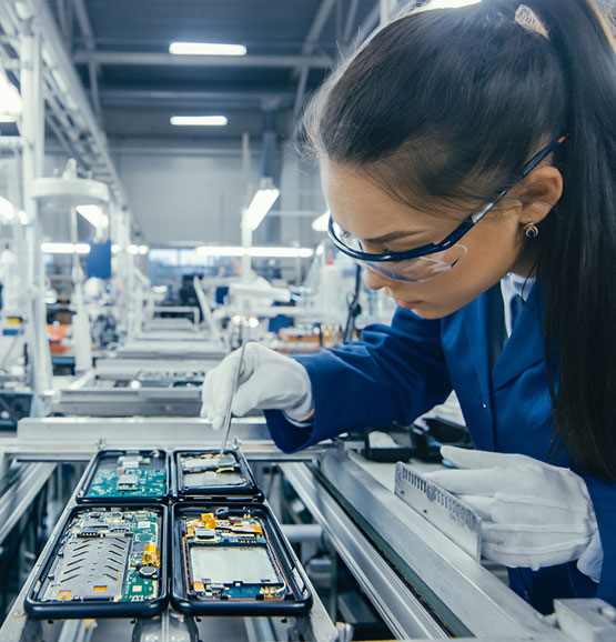 Kvindelig tekniker placerer printplade i fabrikssamlebånd.